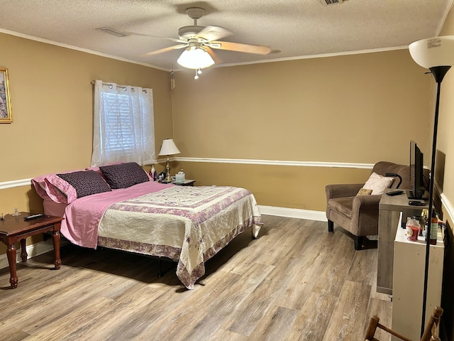 bedroom featuring baseboards, ornamental molding, wood finished floors, a textured ceiling, and a ceiling fan