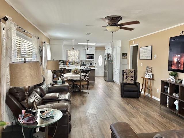 living room featuring visible vents, crown molding, a ceiling fan, and wood finished floors