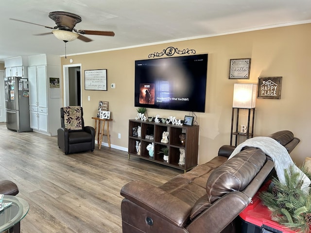 living area featuring crown molding, wood finished floors, baseboards, and ceiling fan