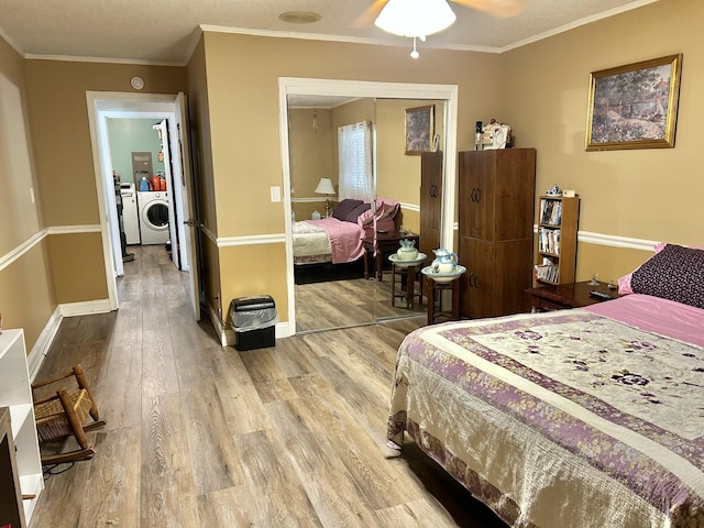 bedroom with wood finished floors, crown molding, washing machine and dryer, and a closet