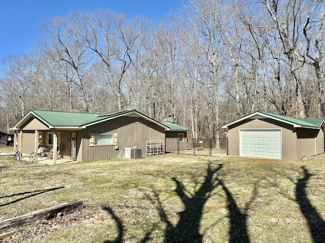 view of home's exterior featuring fence, central AC, a lawn, metal roof, and an outdoor structure