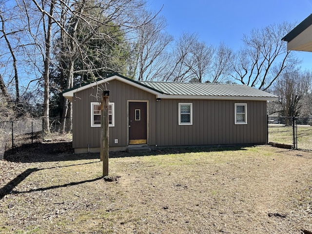 view of front facade with a gate, metal roof, an outbuilding, and fence