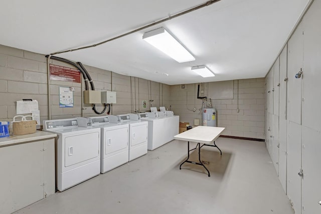 common laundry area featuring concrete block wall, water heater, and independent washer and dryer