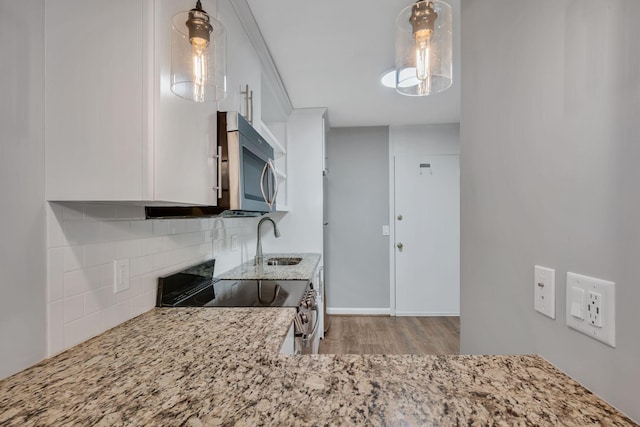 kitchen featuring decorative light fixtures, tasteful backsplash, appliances with stainless steel finishes, white cabinets, and a sink