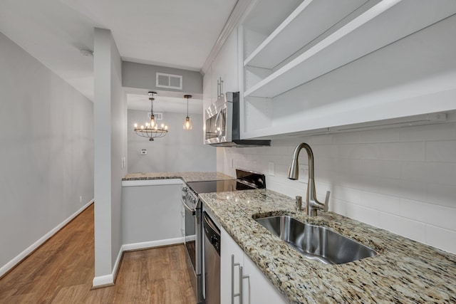 kitchen with a sink, white cabinets, appliances with stainless steel finishes, light stone countertops, and open shelves