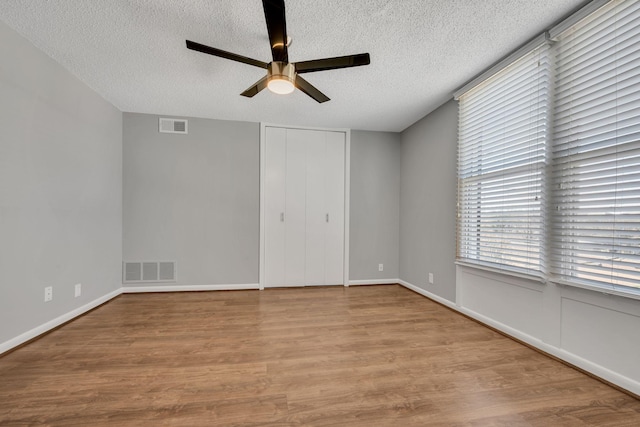 unfurnished bedroom with visible vents, ceiling fan, light wood-style flooring, and a textured ceiling