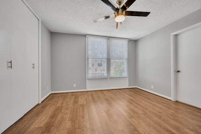 unfurnished bedroom featuring a textured ceiling, ceiling fan, baseboards, and light wood-style floors