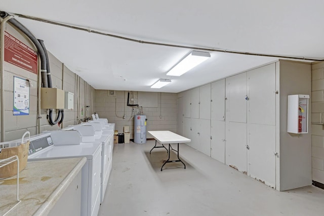 laundry area featuring separate washer and dryer, electric water heater, and concrete block wall