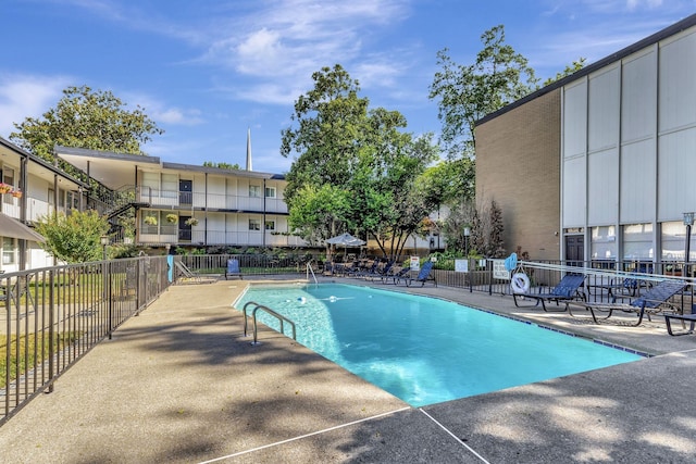 community pool with a patio area and fence