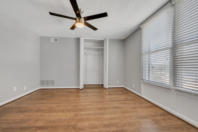 unfurnished bedroom featuring a textured ceiling, light wood-type flooring, visible vents, and a ceiling fan