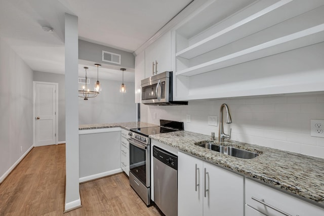 kitchen with pendant lighting, stainless steel appliances, white cabinetry, open shelves, and a sink