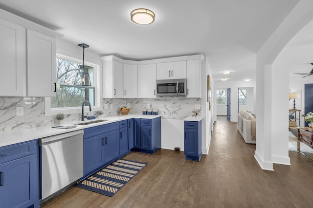 kitchen featuring blue cabinets, a sink, light countertops, appliances with stainless steel finishes, and decorative light fixtures