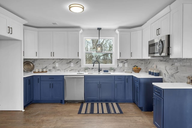 kitchen featuring blue cabinets, appliances with stainless steel finishes, light countertops, and pendant lighting