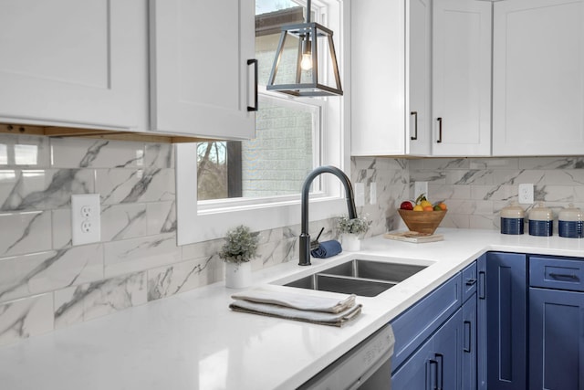 kitchen featuring blue cabinets, a sink, white cabinets, light countertops, and backsplash