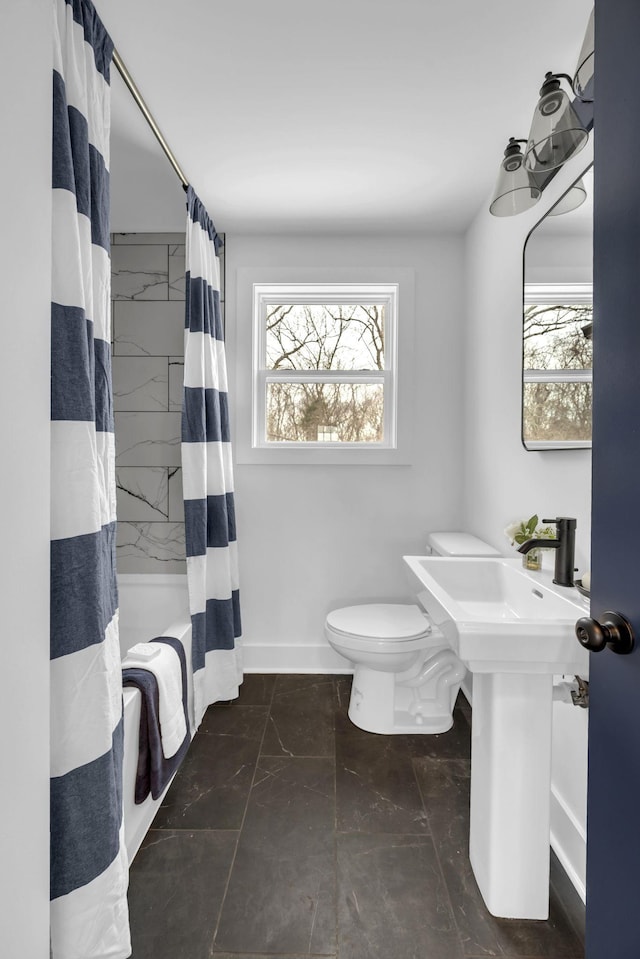 full bathroom featuring shower / tub combo, baseboards, a healthy amount of sunlight, and toilet