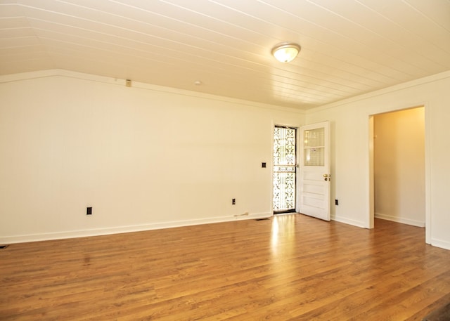 unfurnished room with lofted ceiling, crown molding, baseboards, and wood finished floors