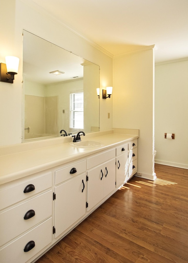 bathroom with toilet, ornamental molding, vanity, wood finished floors, and baseboards