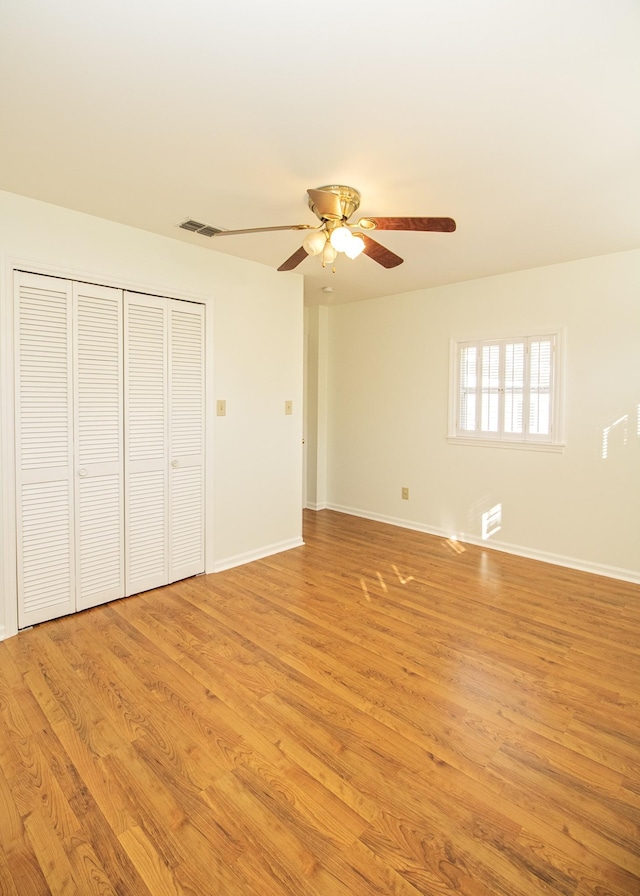 unfurnished bedroom featuring light wood finished floors, visible vents, baseboards, and a closet