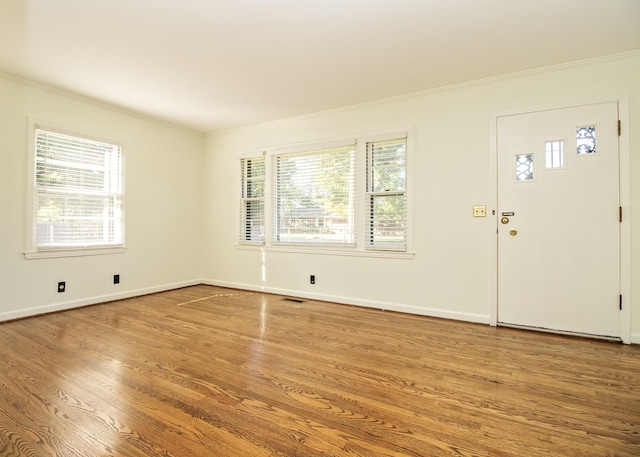 entrance foyer featuring baseboards, wood finished floors, visible vents, and crown molding