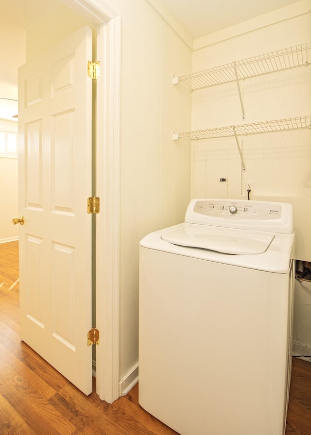 clothes washing area featuring washer / clothes dryer and wood finished floors