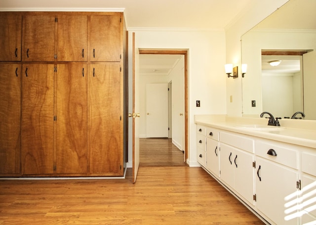 bathroom with baseboards, ornamental molding, wood finished floors, and vanity