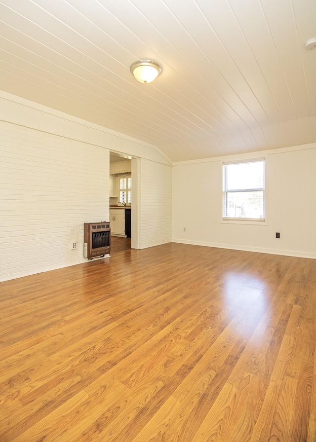 unfurnished living room with wood ceiling, brick wall, heating unit, and wood finished floors