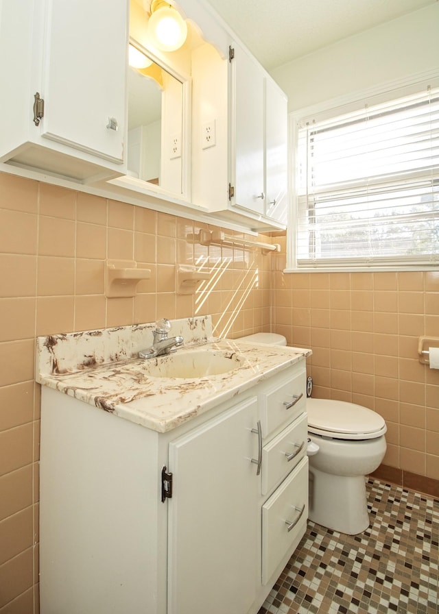 bathroom with toilet, vanity, tile walls, and tile patterned floors