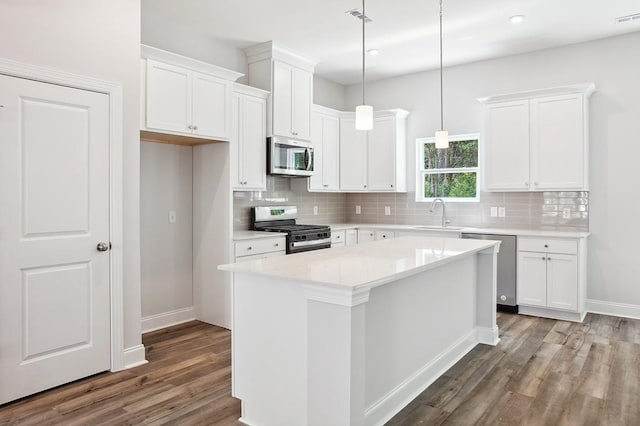 kitchen with a kitchen island, white cabinetry, light countertops, appliances with stainless steel finishes, and pendant lighting