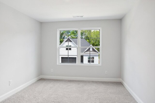 spare room with carpet floors, visible vents, and baseboards