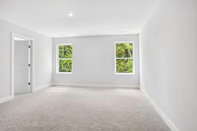 empty room with baseboards, plenty of natural light, and light colored carpet