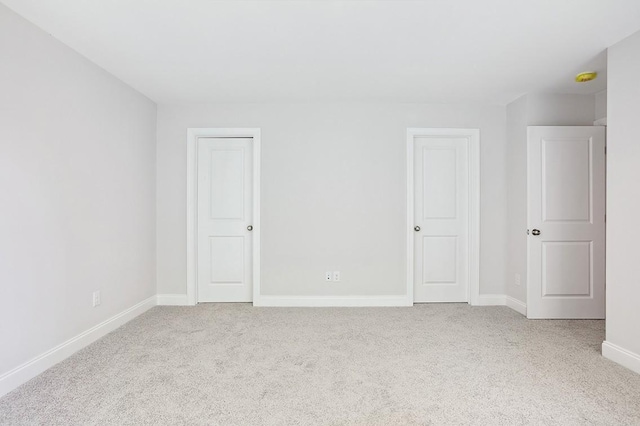 unfurnished bedroom featuring light colored carpet and baseboards