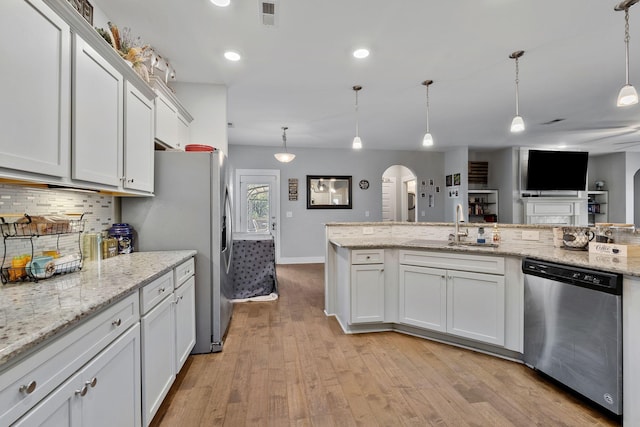 kitchen featuring white cabinetry, appliances with stainless steel finishes, a sink, and decorative light fixtures