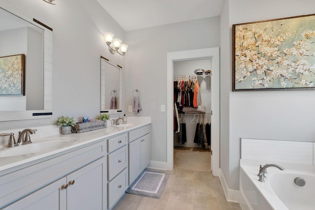 full bathroom with a sink, baseboards, a bath, double vanity, and a walk in closet