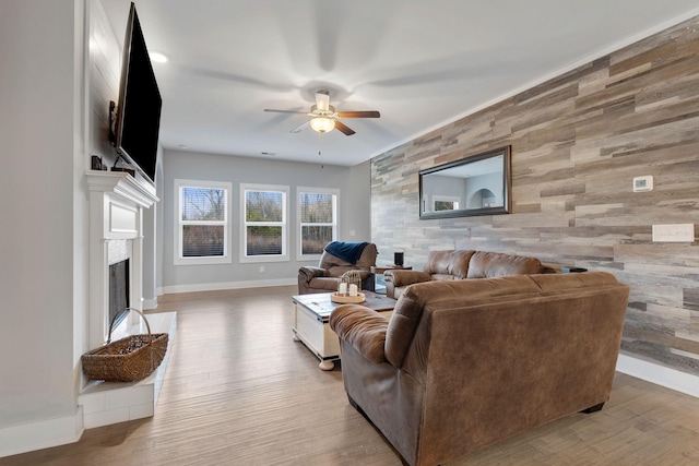 living area featuring an accent wall, a fireplace, wood finished floors, and baseboards