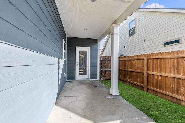 view of exterior entry featuring a patio area and fence