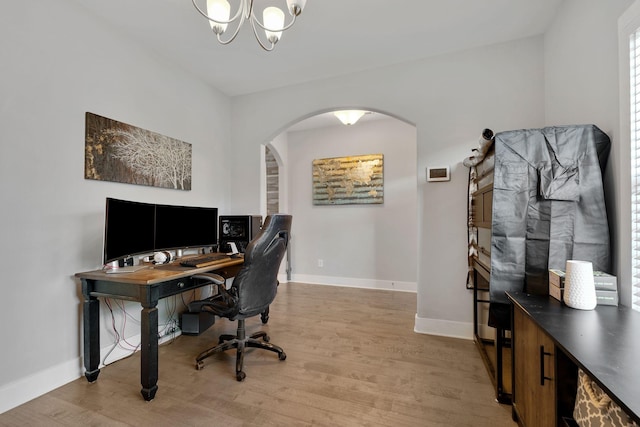 office featuring arched walkways, a chandelier, light wood-style flooring, and baseboards