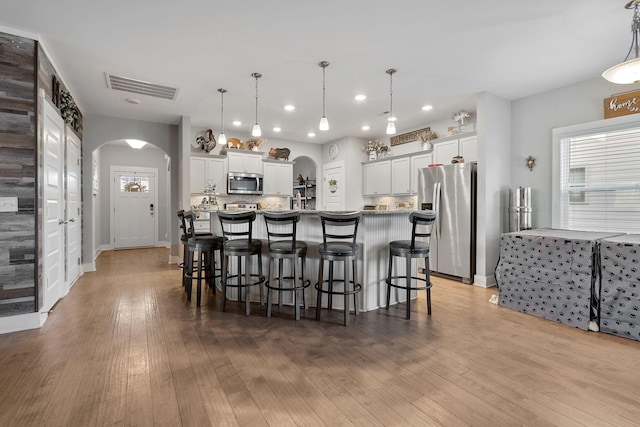 kitchen with arched walkways, visible vents, white cabinets, appliances with stainless steel finishes, and pendant lighting