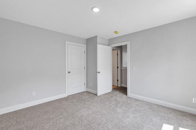 unfurnished bedroom with baseboards and light colored carpet