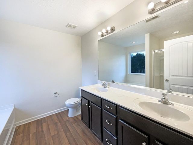 full bath featuring wood finished floors, a sink, visible vents, double vanity, and a stall shower