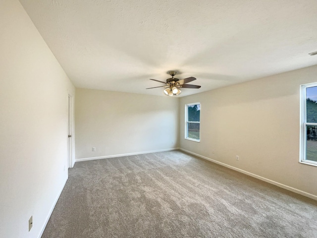 carpeted empty room with ceiling fan, a textured ceiling, and baseboards