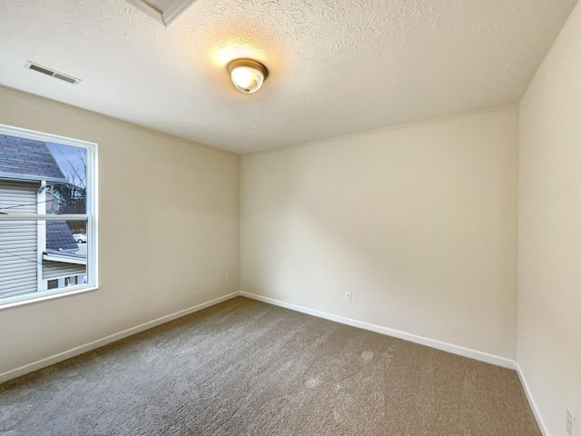 carpeted spare room featuring a textured ceiling, visible vents, and baseboards