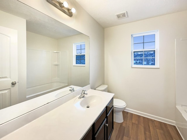 bathroom with toilet, wood finished floors, vanity, visible vents, and baseboards