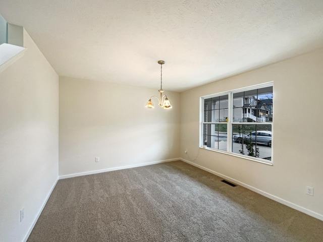 spare room with a chandelier, carpet flooring, visible vents, and baseboards