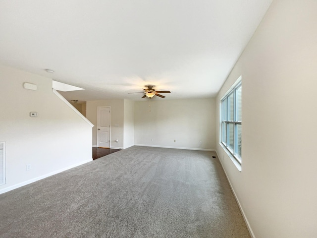 empty room featuring ceiling fan, dark carpet, visible vents, and baseboards