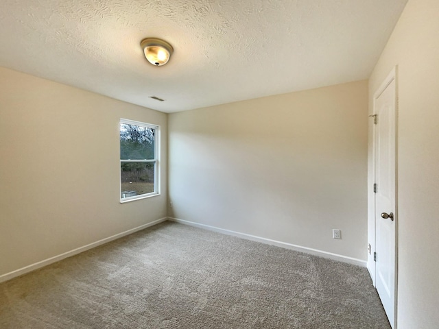 spare room with dark colored carpet, visible vents, a textured ceiling, and baseboards