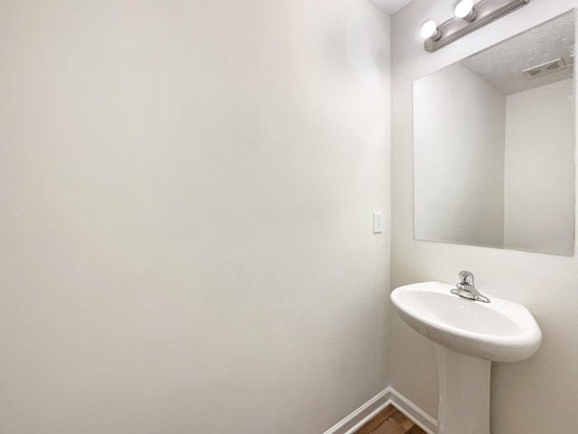 bathroom featuring baseboards, visible vents, and wood finished floors