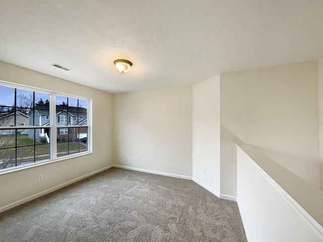 spare room with baseboards, a textured ceiling, visible vents, and carpet flooring