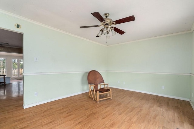 unfurnished room with light wood-type flooring, a ceiling fan, baseboards, and crown molding