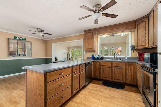 kitchen featuring a peninsula, a sink, appliances with stainless steel finishes, light wood-type flooring, and brown cabinetry