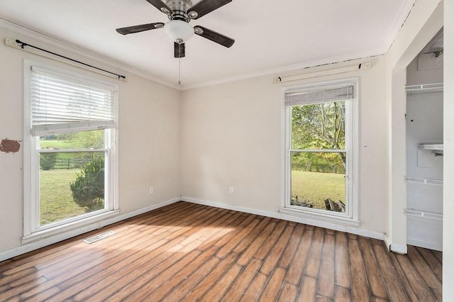 unfurnished room featuring plenty of natural light, visible vents, dark wood finished floors, and crown molding